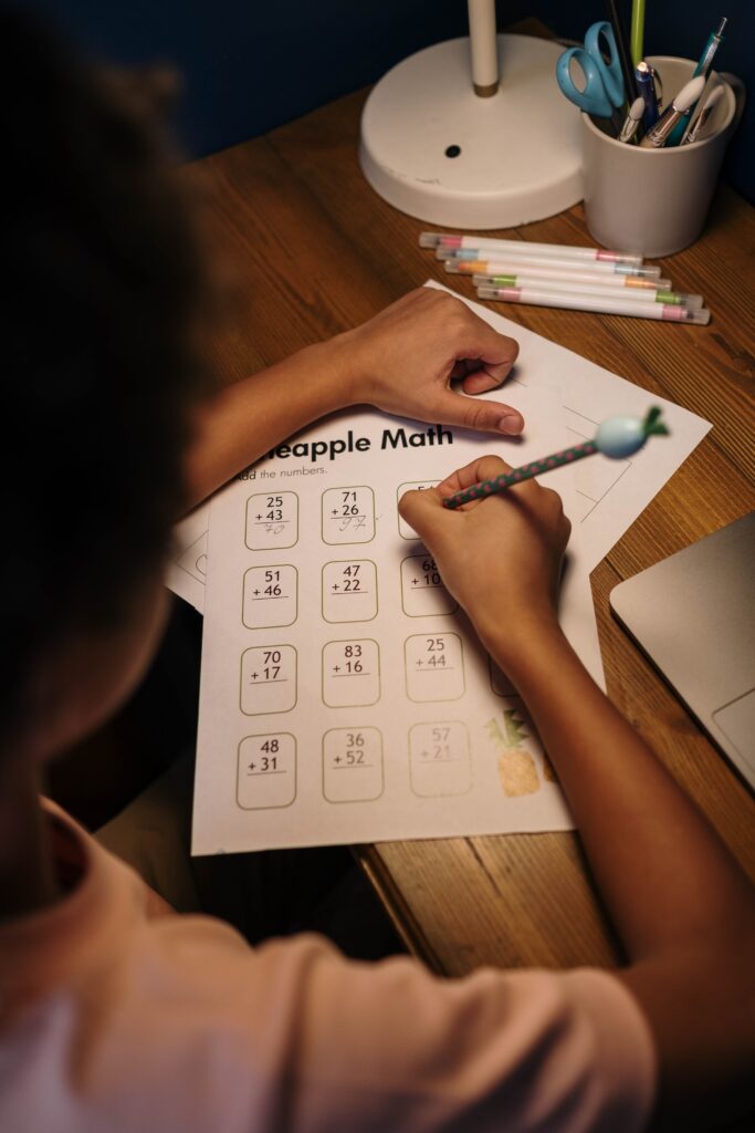 A child focuses on solving a math worksheet at a home study desk, fostering learning and concentration.