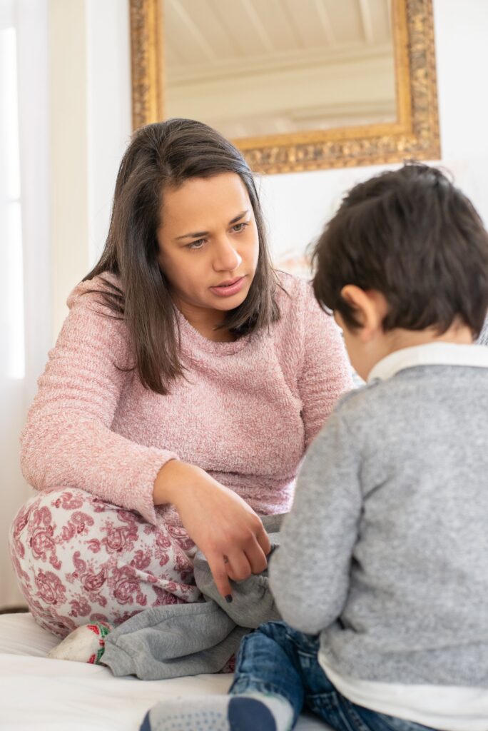 A mother engaging with her young son indoors, capturing a moment of warmth and care.